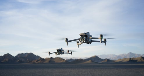 Twee drones vliegen met gebergte in de achtergrond