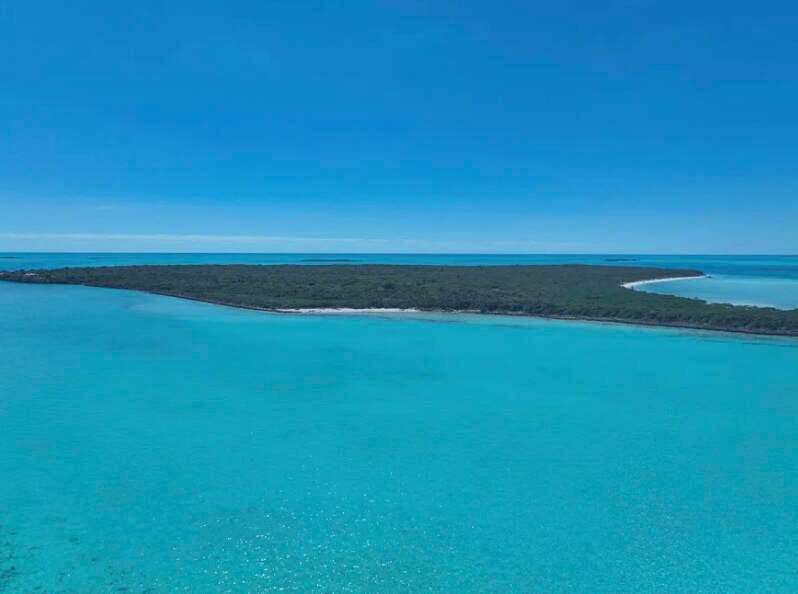 A private remote tropical island with blue waters and blue sky