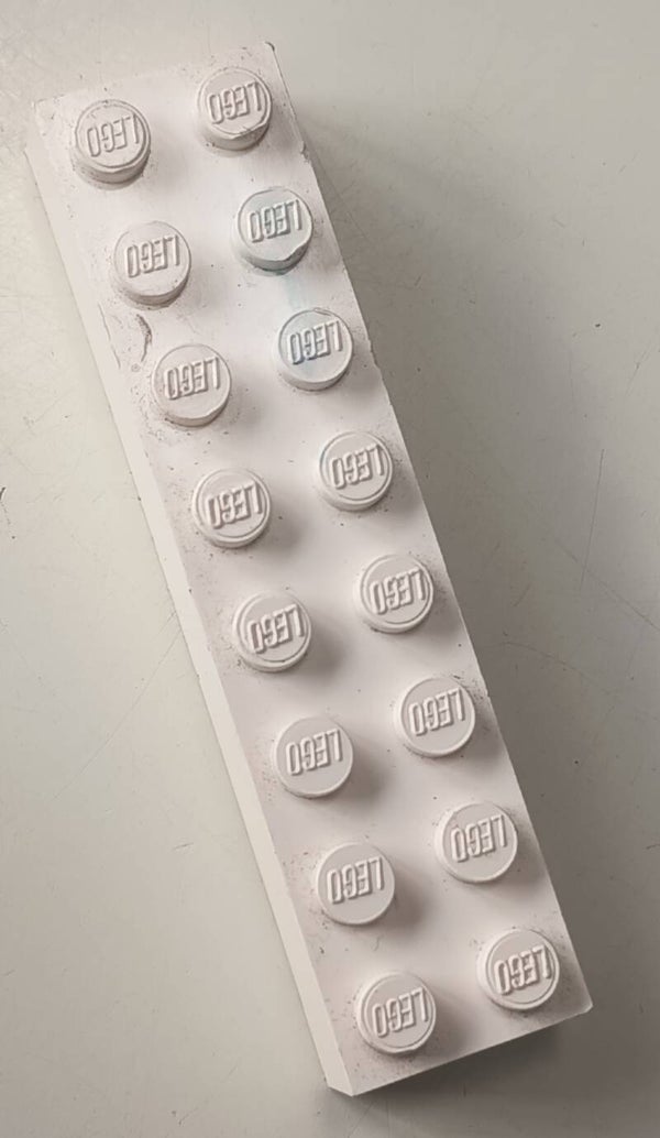 White 2 x 8 brick with a little blue marbled