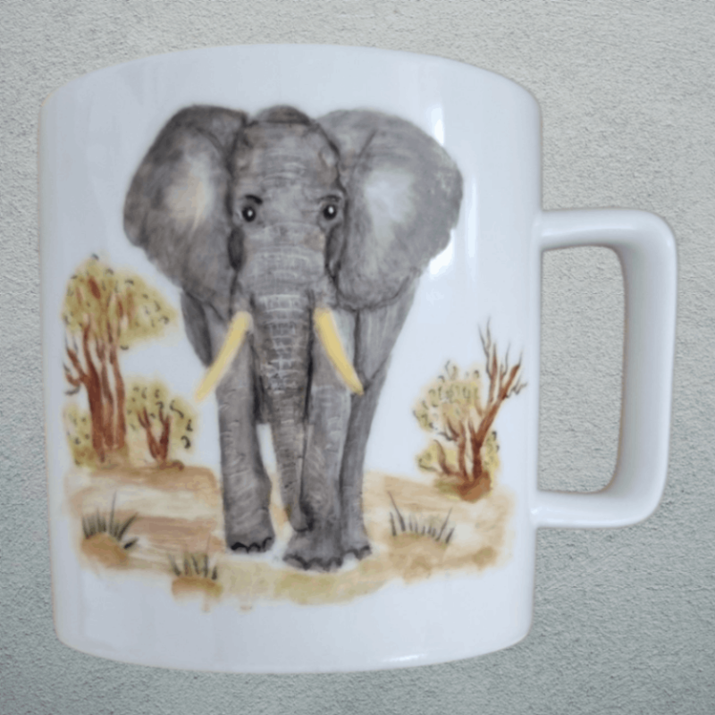 Handbemalte Porzellantasse mit realistischem Elefantenmotiv in Naturkulisse.