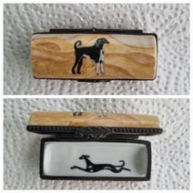 Eine längliche Porzellanpillendose zeigt außen einen stehenden Windhund in der Wüste, innen einen rennenden Windhund – beide liebevoll bemalt.