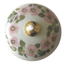 Eine kleine runde Petrolllampe ist mit einem zarten Kranz aus rosa Heckenrosen verziert.
