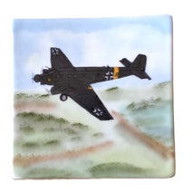 Ein Porzellan-Pfannenuntersetzer zeigt ein Militärkrankenflugzeug beim Flug – technisch genau gemalt.