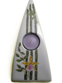 Ein segelförmiger Teelichthalter zeigt Bambus und eine zarte Orchidee, bemalt in Naturfarben.