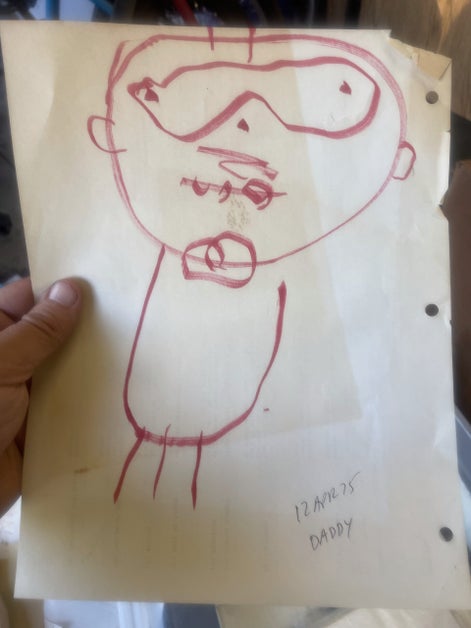 a child's drawing of a man with glasses and a mustache. The caption reads "12 APR 75 DADDY"