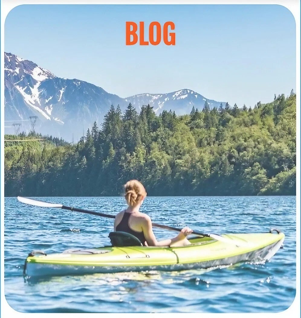 Image of a woman canoeing on water with a landscape of trees and mountains in the background