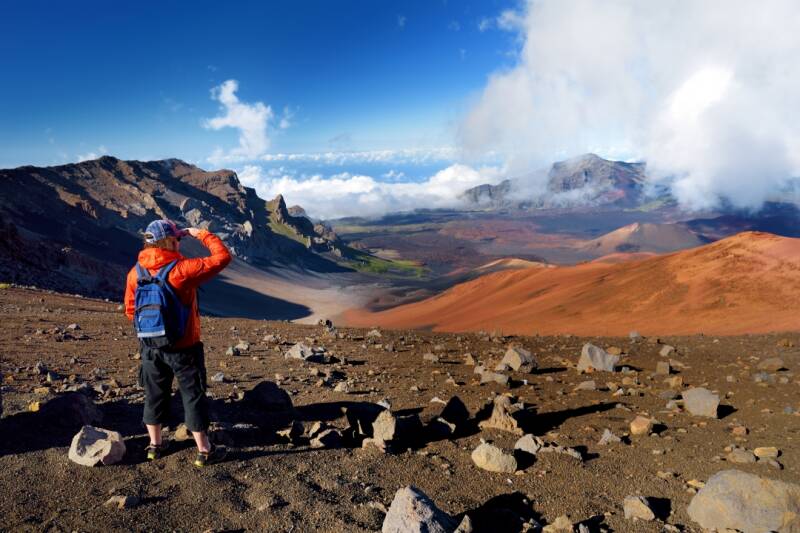 Tourist hiking in Haleakala volcano crater on the Sliding Sands trail. Beautiful view of the crater floor and the cinder cones below. Maui, Hawaii