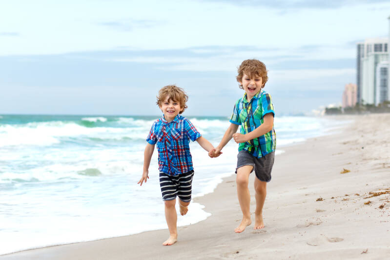 Two little kids boys running on the beach of ocean