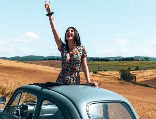 Girl waving when coming out of the roof of the 500 Fiat, during the 500 Vintage Tour on Chianti Roads