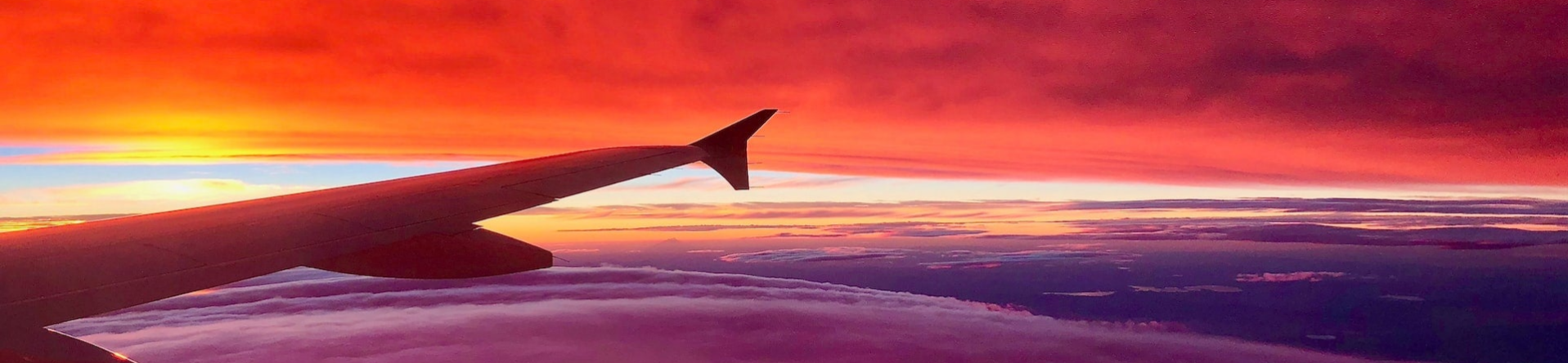 Wing of an airplane in flight with sunrise in the background