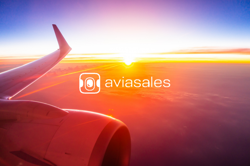 Image of a photo taken from an airplane window, with the sunrise and the aviasales logo, article of partnership with winkyes travel linked to trees for free carbon offsetting