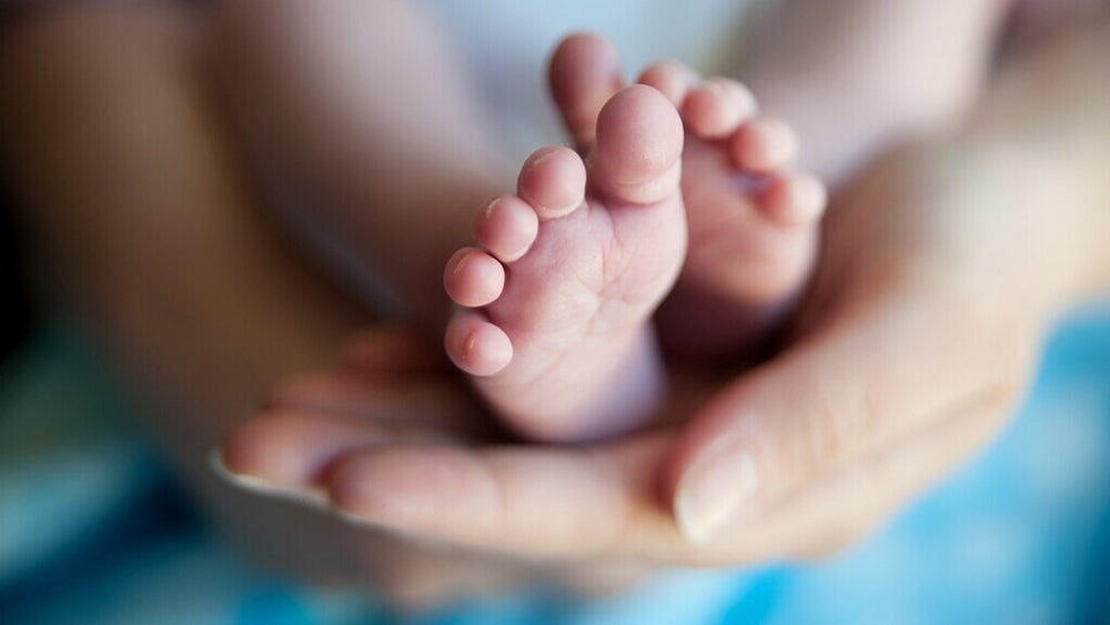 Een babyhandje in de hand van een ouder