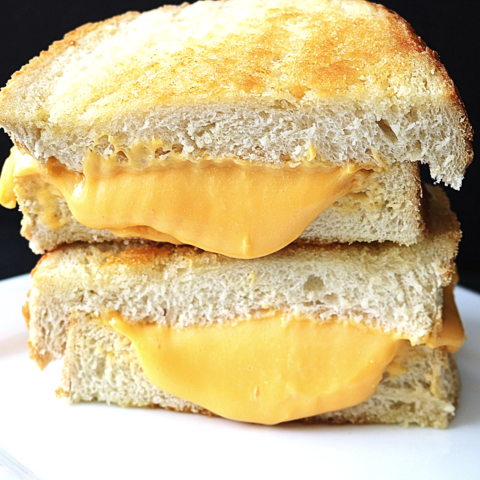 A crispy, golden-brown grilled cheese sandwich on thick Texas toast with melting cheddar cheese oozing out the sides