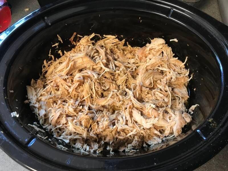 A slow-cooker full of tender, shredded Cannabis Crockpot Chicken, perfect for cannabis edibles and stoner strategies enthusiasts.