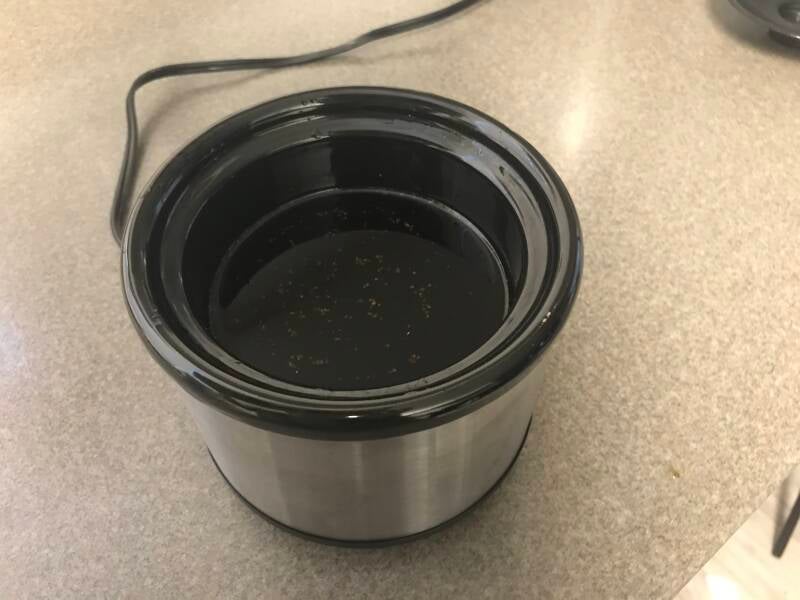 Crockpot filled with golden cannabis oil, being prepared for straining for homemade edibles