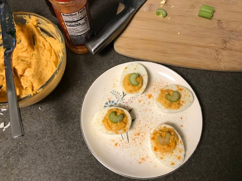 A tray of Buffalo Cannabis Deviled Eggs garnished with celery, a favorite appetizer for cannabis edibles and Stoner Strategies enthusiasts 