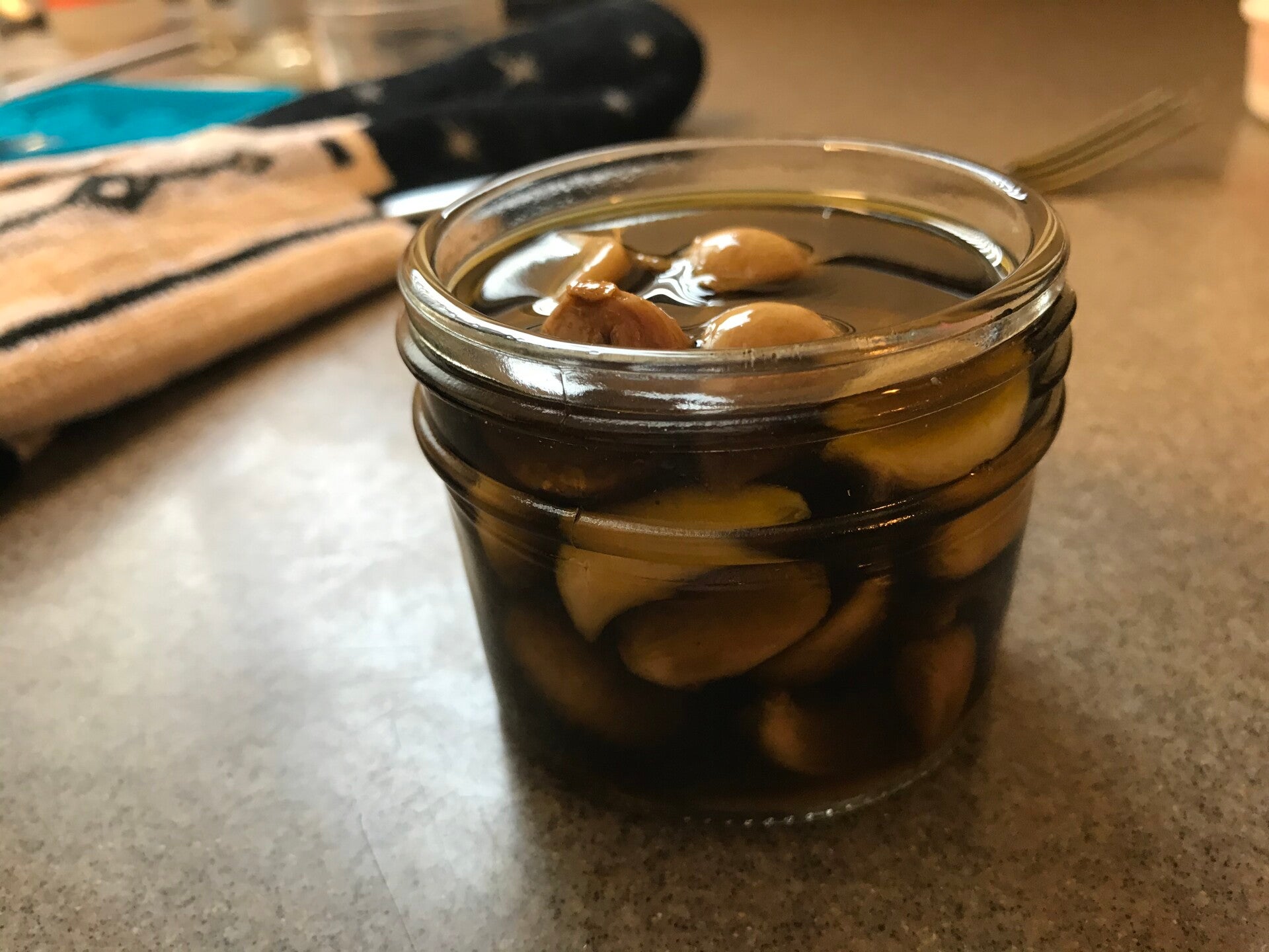 A glass jar of homemade Cannabis Garlic Confit, perfect for cannabis edibles and Stoner Strategies enthusiasts