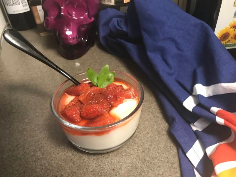 A bowl of fresh basil and strawberries coated in golden cannabis honey, a perfect dessert choice for cannabis edibles and Stoner Strategies readers