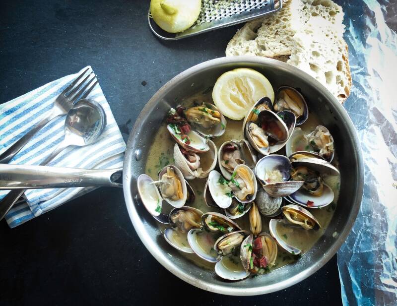 A bowl of Cannabis White Wine Garlic Clams with crusty bread, perfect for cannabis edibles and stoner strategies enthusiasts.
