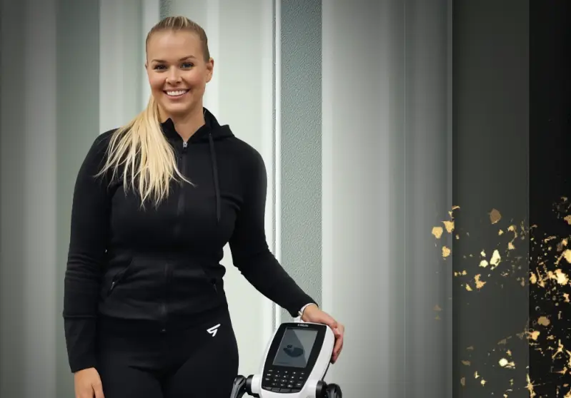 Hymyilevä nainen seisoo InBody-kehonkoostumusmittauslaitteen vieressä.
