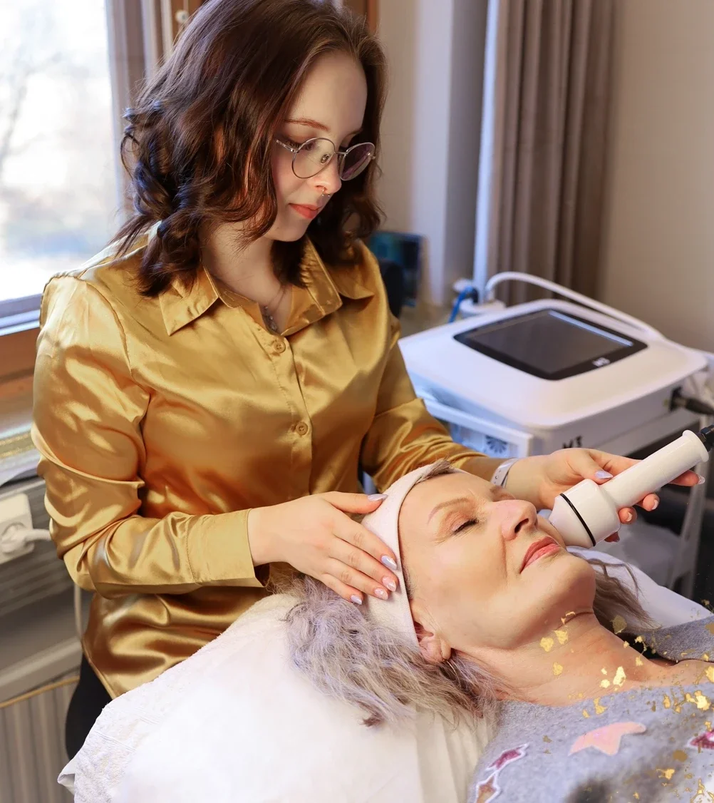 Nainen makaa hoitopedillä ja kosmetologi käsittelee hänen kasvojaan tehokkaalla radiofrekvenssihoidolla.