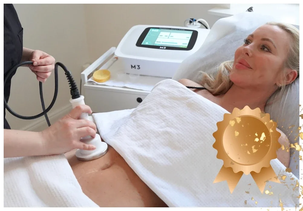 Nainen makaa hoitopedillä vartalonmuokkaushoidossa, jossa käytetään rasvanpoistolaitetta vatsan alueella. Kuvan oikeassa alalaidassa on prossinen mitali, joka kuvastaa tuotepakettia.