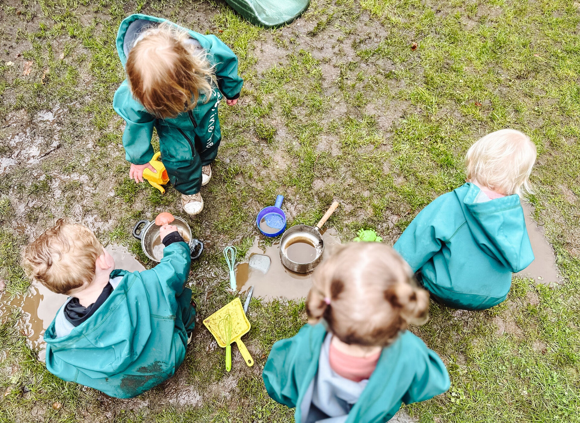 Vier kinderen maken buiten moddersoep met pannetjes en schepjes bij De Kleine Held in Doetinchem.