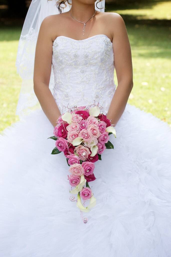 mariée dans sa très belle robe pour son grand jour avec une magnifique composition bouquet de roses qui illumine la mariée