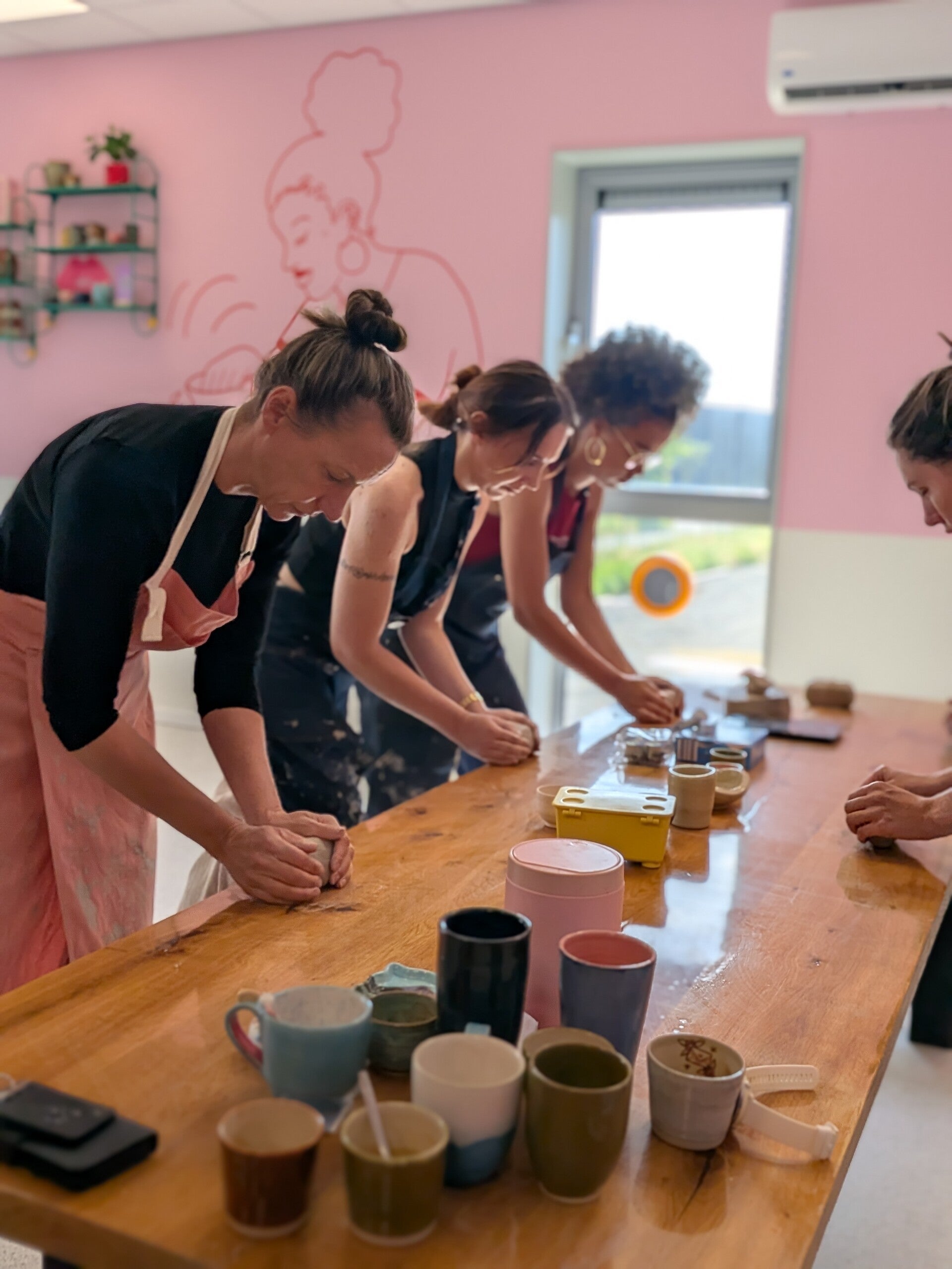 Drie personen die lol hebben en lachend klei aan het kneden zijn tijdens een cursus pottenbakken