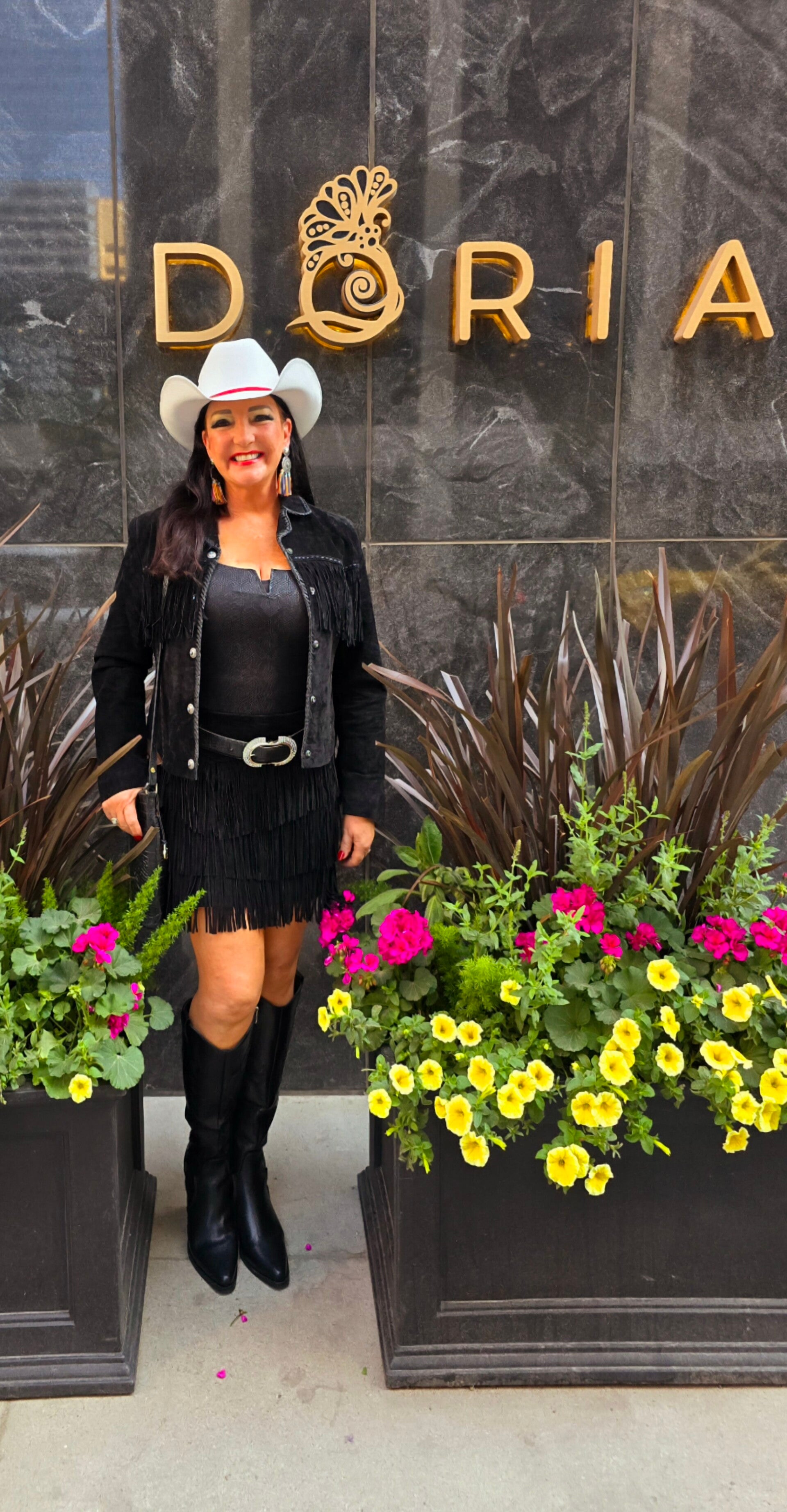 Travel journalist Terri Guthrie showcasing Texas western fashion outside of Doria, surrounded by flower pots in Calgary, Canada.