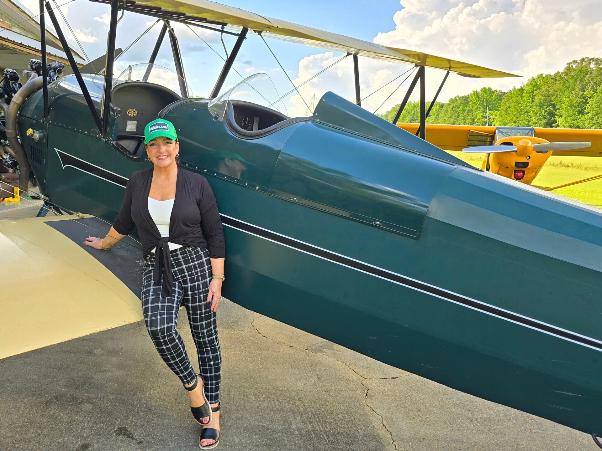 Travel journalist Terri Guthrie leaning on a historic 1929 biplane during a Vintage Air Tours excursion in Ridgeland, Mississippi.