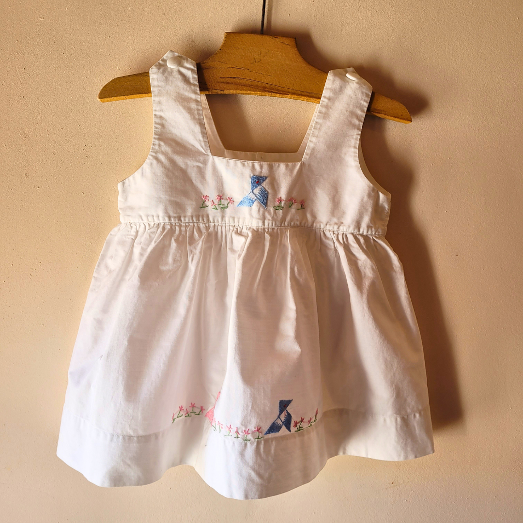 Robe de bébé aux cocottes bleues brodées – Une tendre évocation de la petite enfance