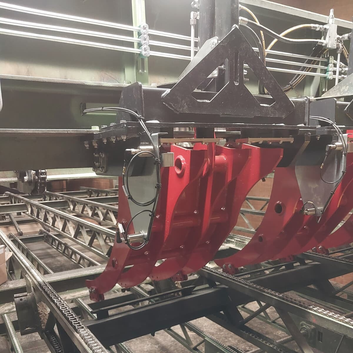 Vier hydraulisch betätigte Schwenkarme zur Umlenkung von Holzprodukten