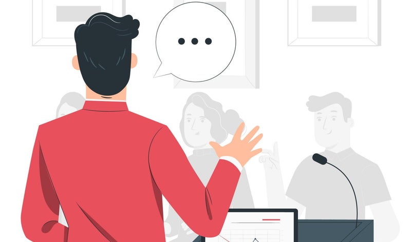 Mann in rotem Jacket steht vor Menschengruppe und spricht