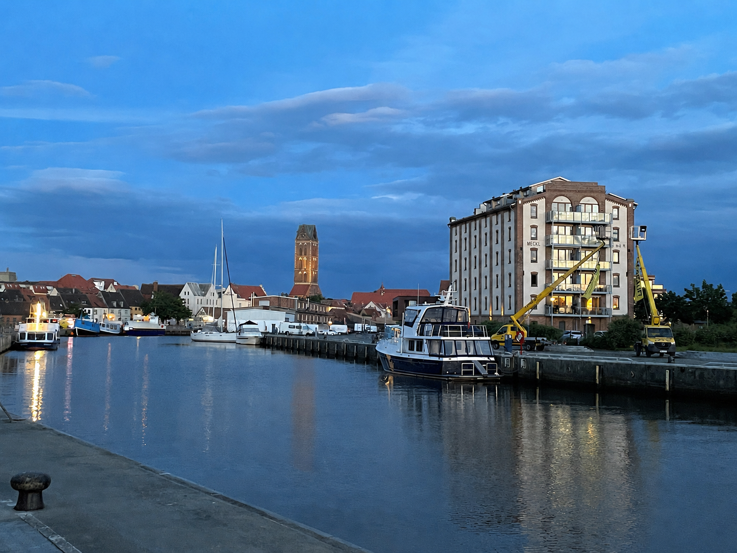 Alter Hafen von Wismar mit Booten, historischem Speicher und dem Turm der Marienkirche in der Abenddämmerung