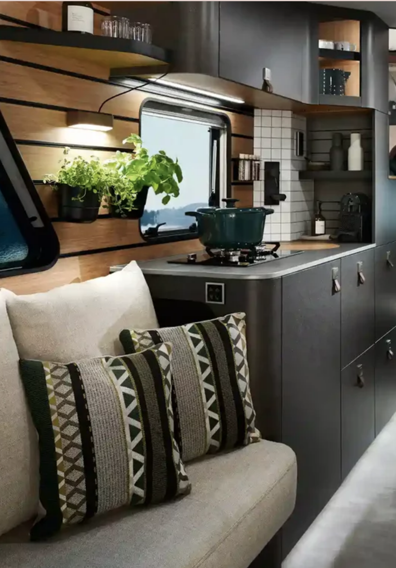 Cuisine équipée du Hymer Venture S avec plaque de cuisson, casserole et plantes aromatiques près de la fenêt