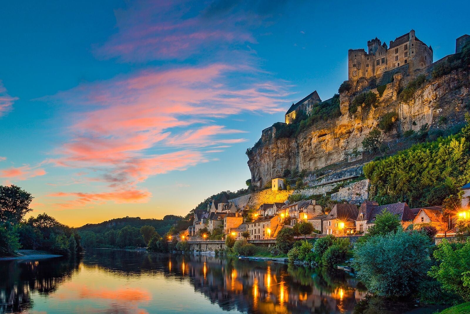 Village médiéval de Beynac-et-Cazenac en Dordogne avec château sur la falaise et rivière Dordogne au coucher du sol