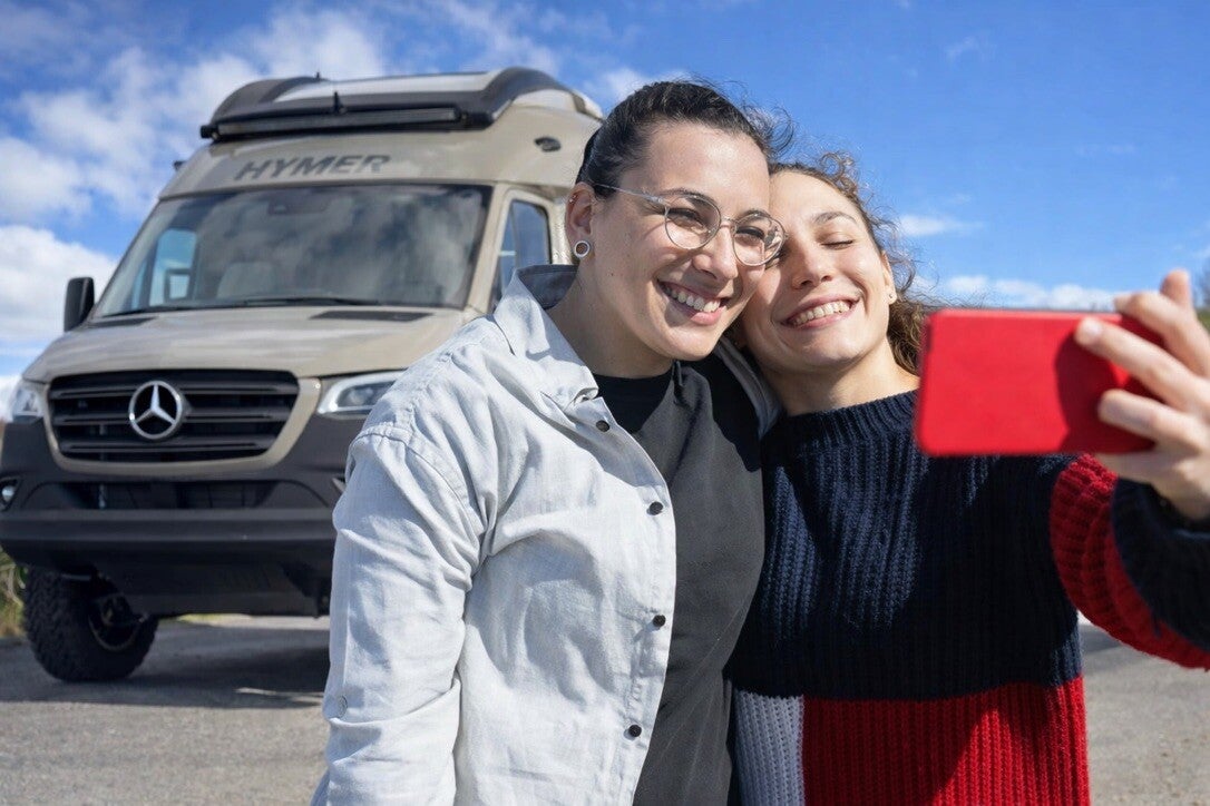Couple en road trip prenant un selfie devant le camping-car Hymer Venture S.