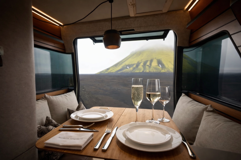 Espace repas du Hymer Venture S avec table dressée, banquettes et vue panoramique sur un paysage volcanique.