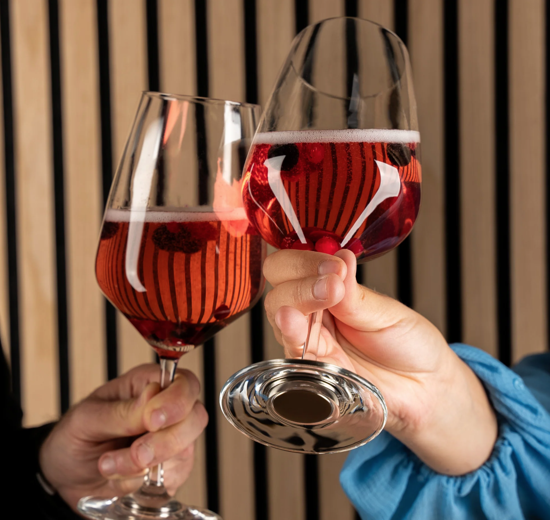 Moment convivial dans le Hymer Venture S avec deux verres de vin rosé trinquant dans un intérieur en bois