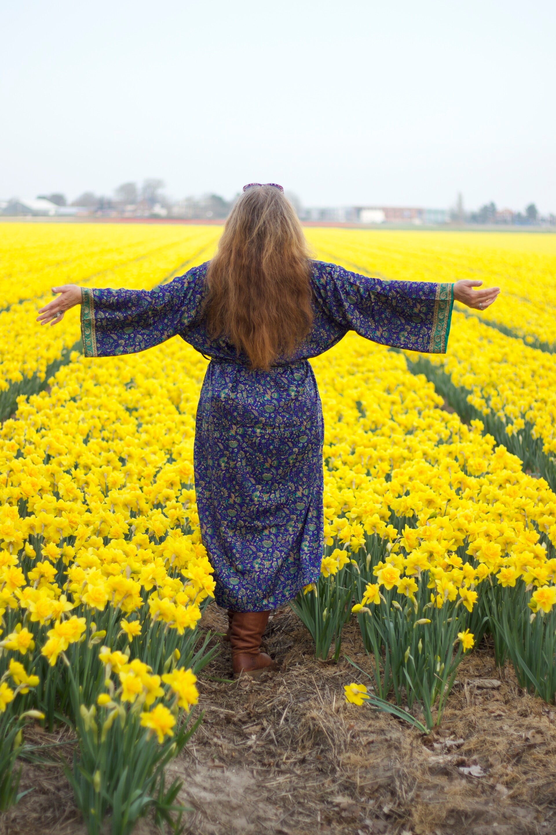 Marianne Pheil met open armen in een veld vol narcissen