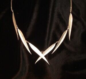 Gold, handmade necklace with a black background. 