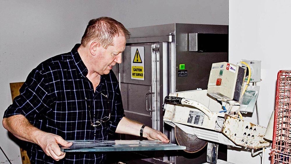 Sean Egan using a machine to create art glass in his workshop. 
