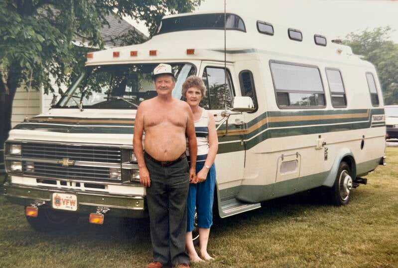 Shirtless man with his wife in front of an RV.