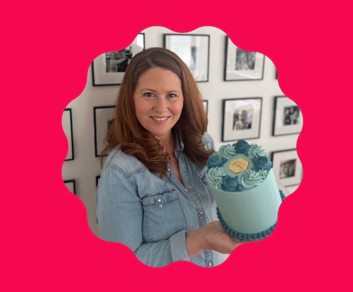 Debora, owner of Foxy Bakes holding one of her occasion cakes, decorated in blue swiss meringue buttercream.