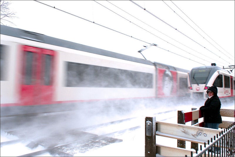 onbewaakte overweg tussen Valkenburg en Schin op Geul in de sneeuw met passerende Veolia treinstellen