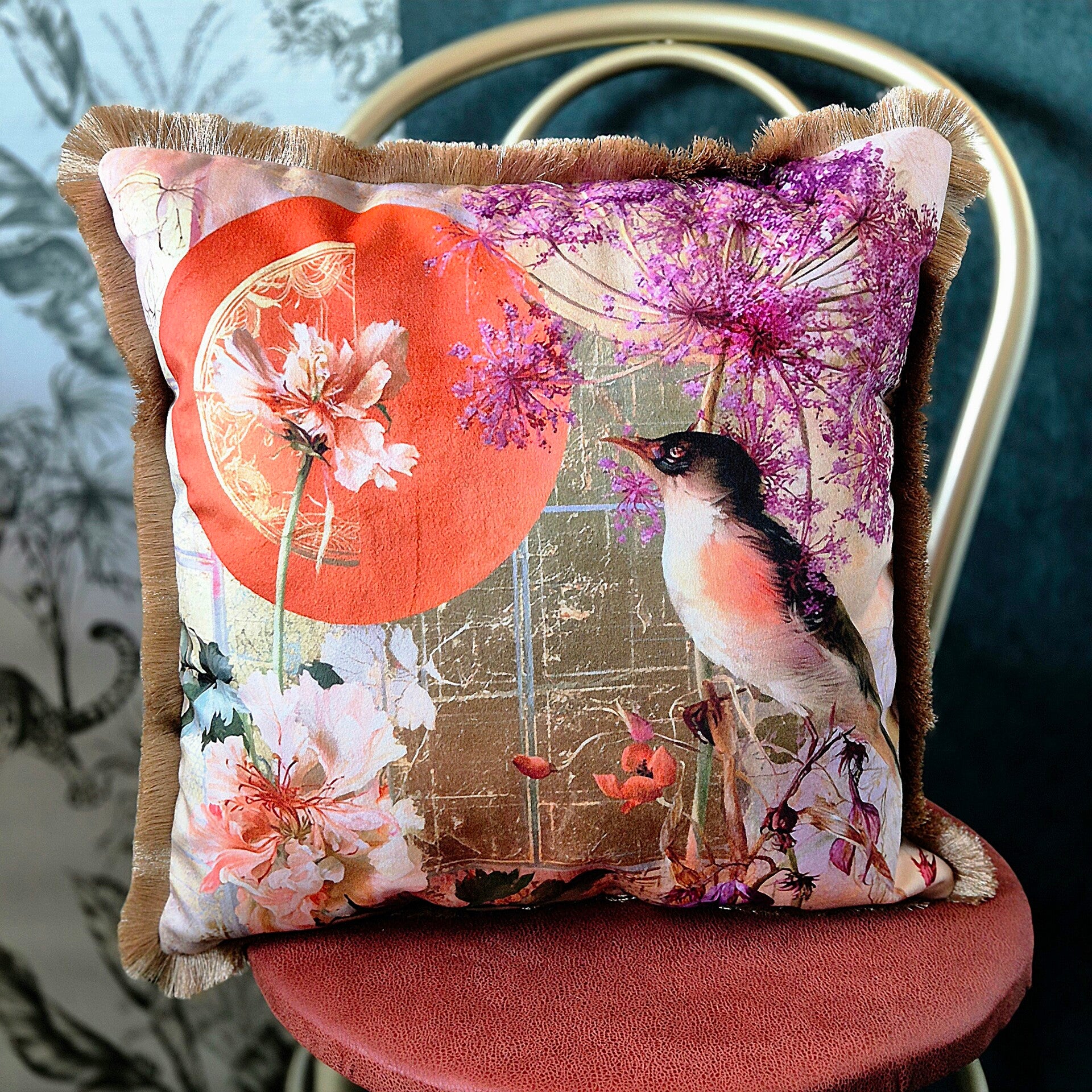 Luxe velours sierkussen met een gedetailleerde botanische print van een vogel en bloemen in paars, oranje, wit en goud, afgewerkt met een goudkleurige franje rand.
