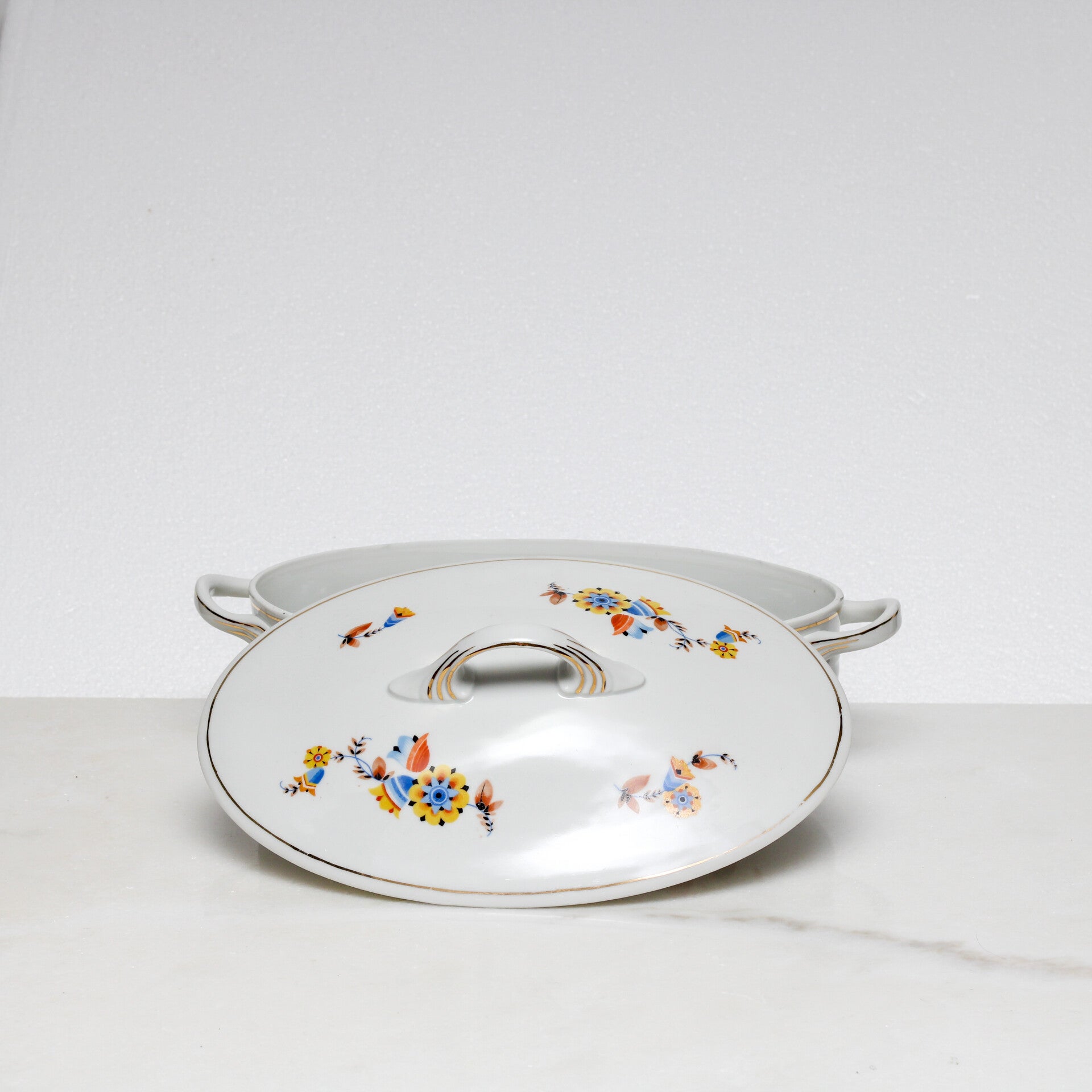 Mosa Maastricht ovale dekschaal met een geel-blauw bloemmotief en een goudkleurige rand