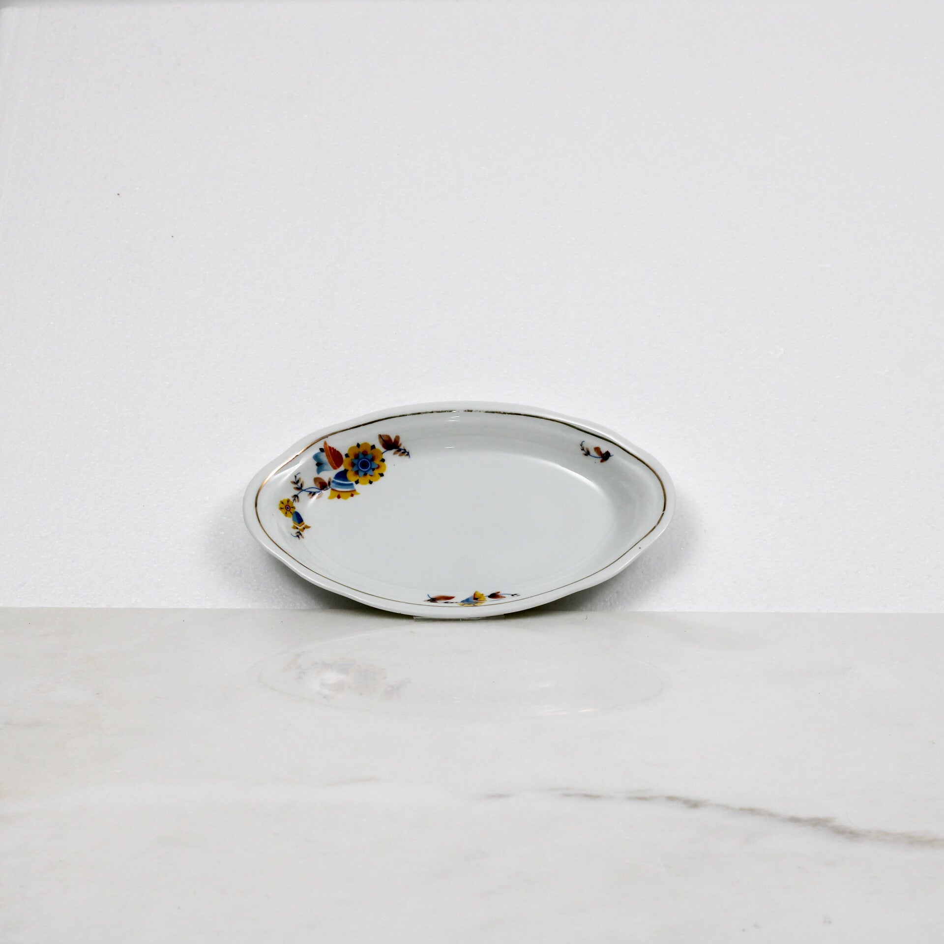 Mosa Maastricht ovaal serveerschaaltje met een geel-blauw bloemmotief en een goudkleurige rand