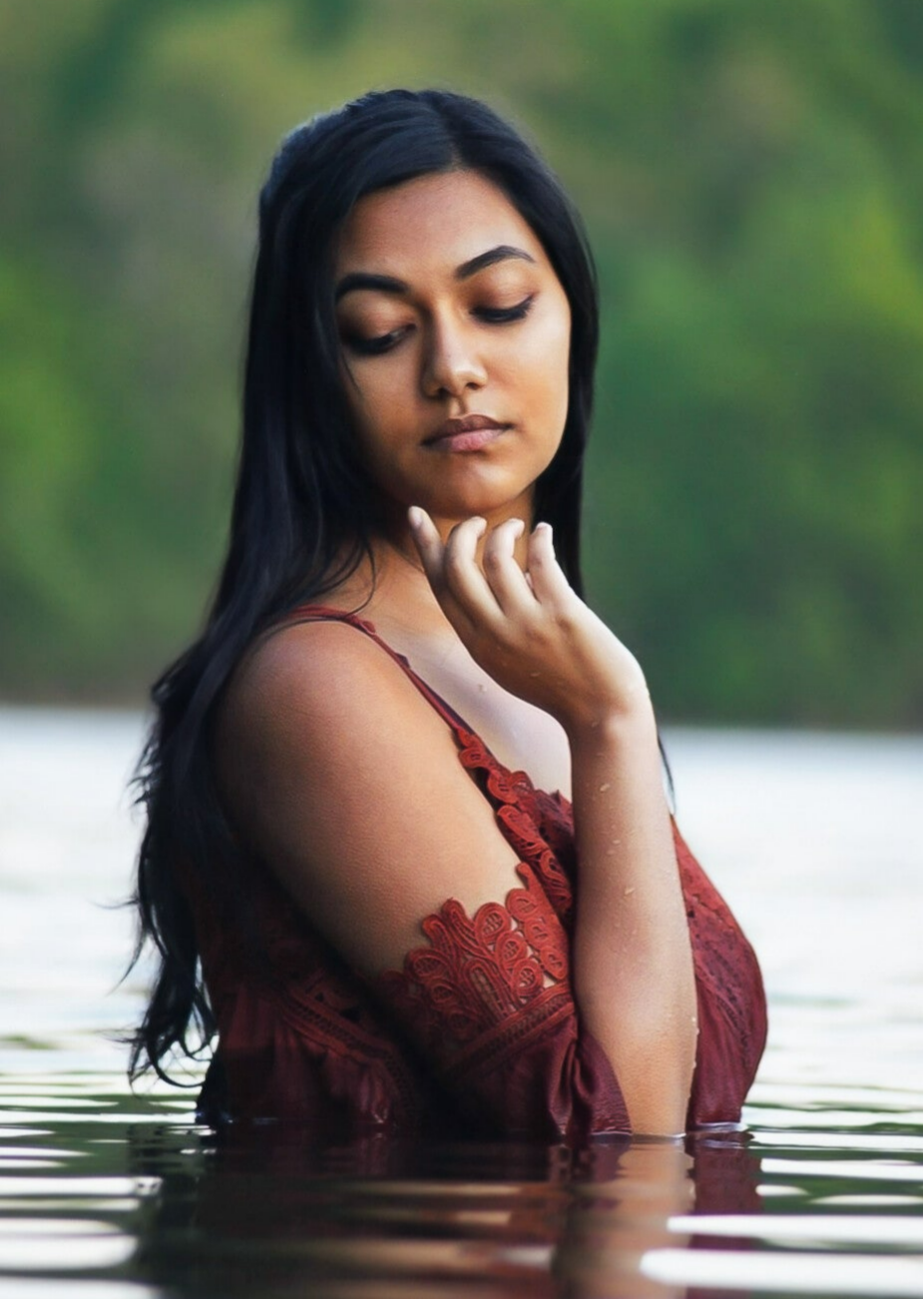 Individual portrait of a woman standing in a lake wearing a red dress with trees in the background at a lake in Southern Maryland.